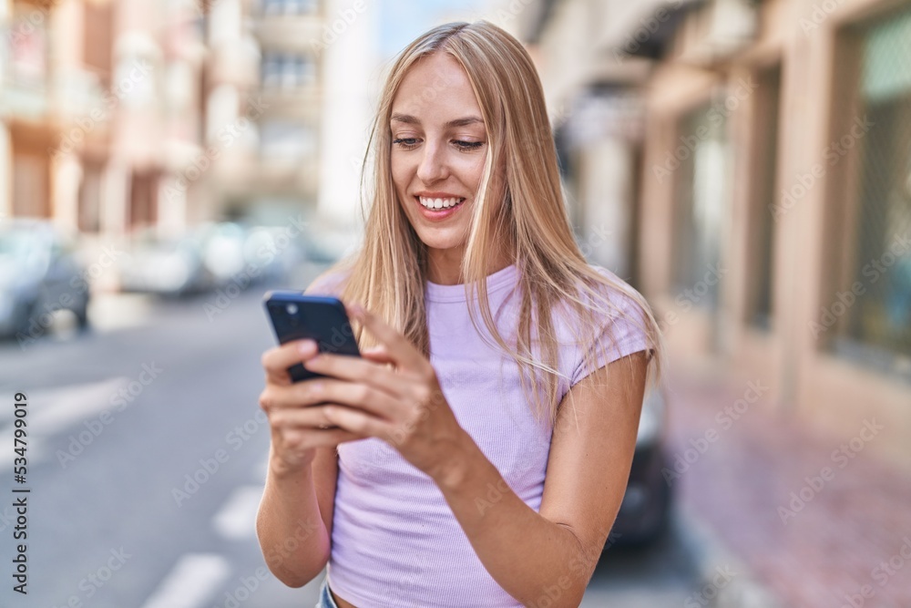 © Krakenimages.com - Young blonde woman smiling confident using smartphone at street © Krakenimages.com - Young blonde woman smiling confident using smartphone at street