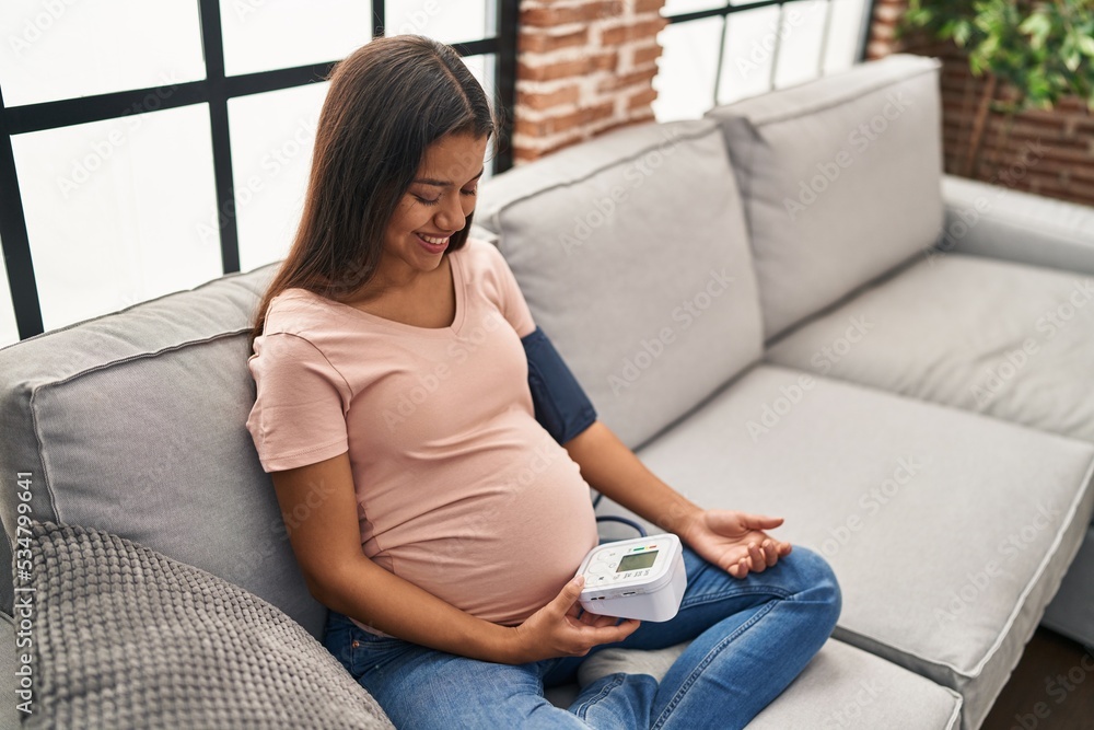 Young latin woman pregnant using tensiometer at home Young latin woman pregnant using tensiometer at home