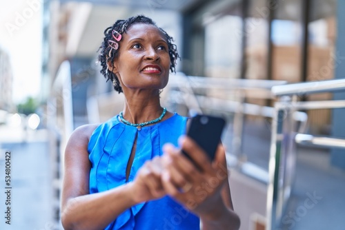 Middle age african american woman smiling confident using smartphone at street