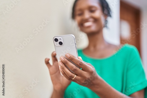 Middle age african american woman smiling confident using smartphone at street