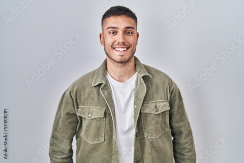 Young hispanic man standing over isolated background with a happy and cool smile on face. lucky person.