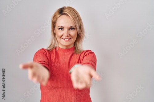 Wallpaper Mural Blonde woman standing over isolated background smiling cheerful offering hands giving assistance and acceptance. Torontodigital.ca