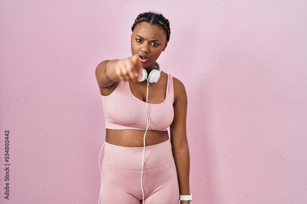 African american woman with braids wearing sportswear and headphones pointing displeased and frustrated to the camera, angry and furious with you