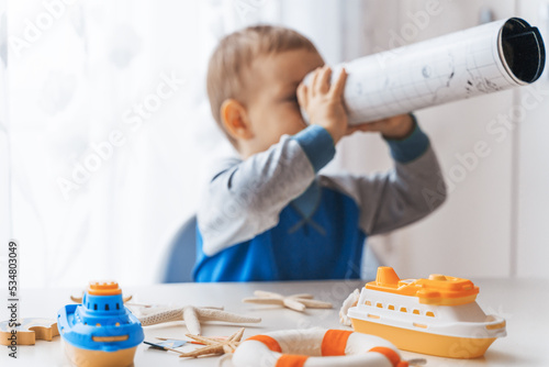 Wallpaper Mural Child play with spyglass, sea shells and boats. Summer vacation and travel concept. Kid play with lifebuoy and starfish Torontodigital.ca