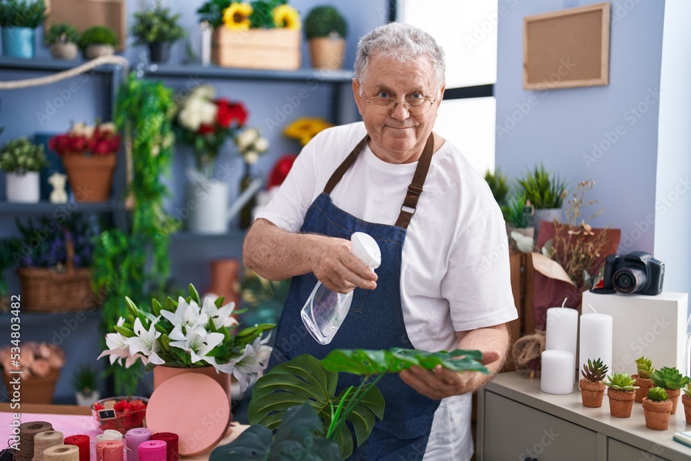 Middle age grey-haired man florist using diffuser working at florist Middle age grey-haired man florist using diffuser working at florist