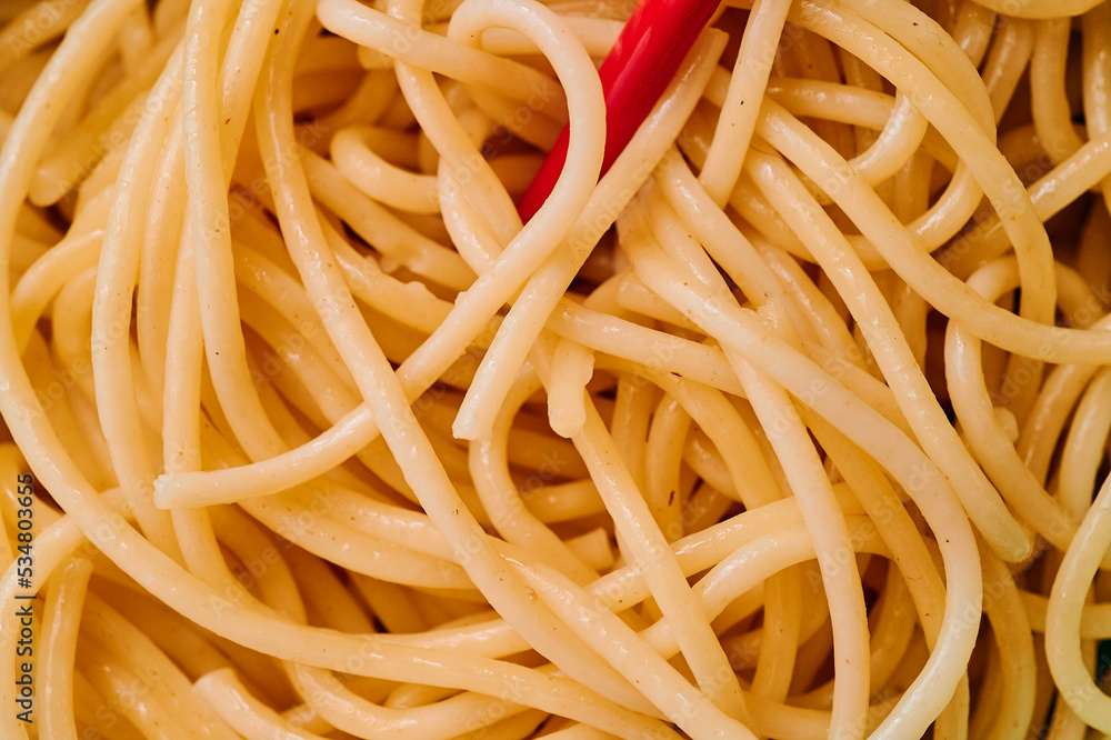 A bowl of pasta is photographed in detail with red chopsticks in a teal dish A bowl of pasta is photographed in detail with red chopsticks in a teal dish