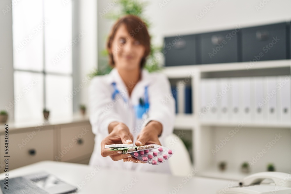Young doctor woman holding pills smiling looking to the side and staring away thinking. Young doctor woman holding pills smiling looking to the side and staring away thinking.