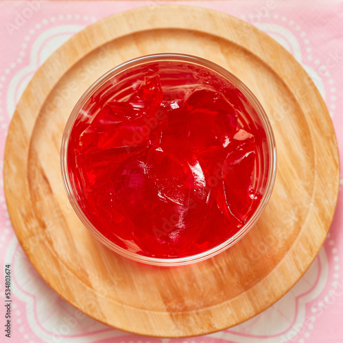 Foto Organic strawberry jello is served in a small glass cup and set on a bamboo plat