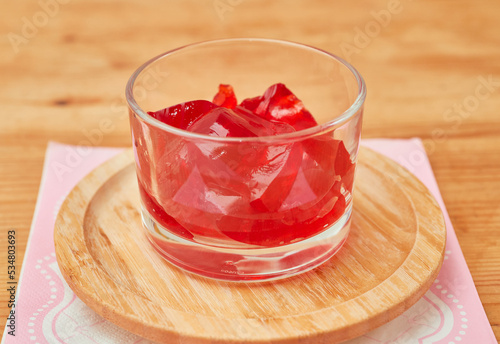 Organic strawberry jello is served in a small glass cup and set on a bamboo plate over a pink napkin