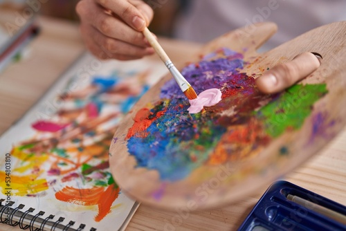 Young arab man mixing color on palette at art studio
