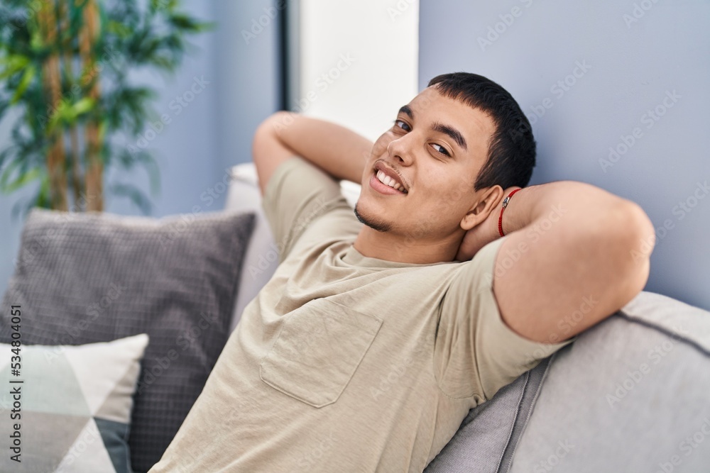 Young man relaxed with hands on head sitting on sofa at home Young man relaxed with hands on head sitting on sofa at home