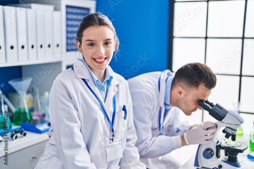 Man and woman scientists smiling confident microscope at laboratory
