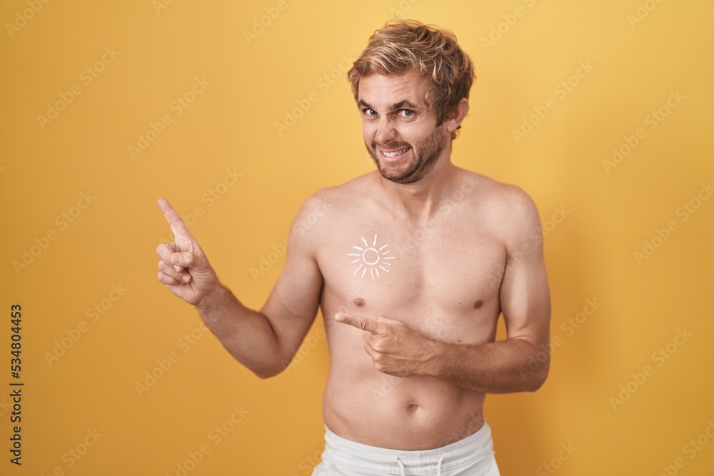 Caucasian man standing shirtless wearing sun screen pointing aside worried and nervous with both hands, concerned and surprised expression