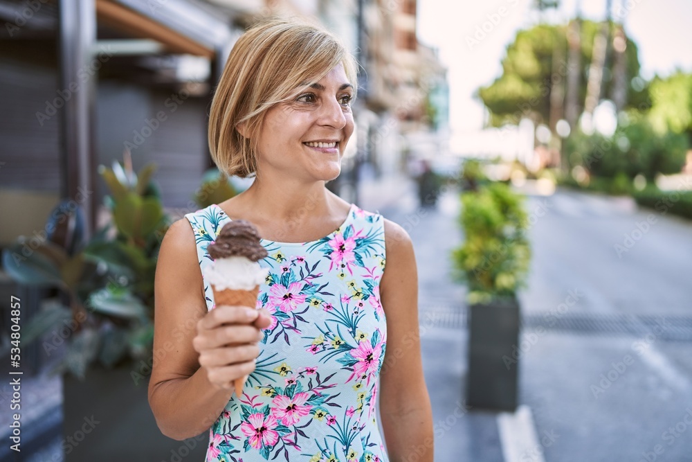 Middle age beautiful woman holding ice cream at park