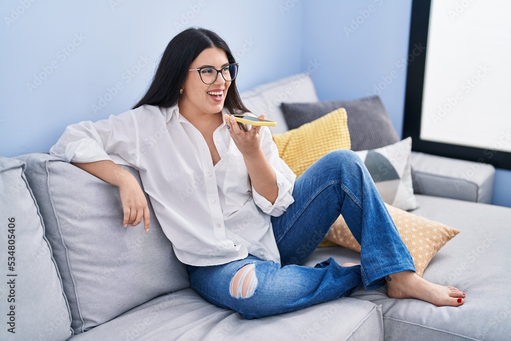 Young hispanic woman talking on the smartphone sitting on sofa at home Young hispanic woman talking on the smartphone sitting on sofa at home