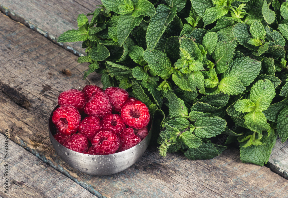 Bowl with fresh ripe raspberries on a wooden table. Raspberry and mint