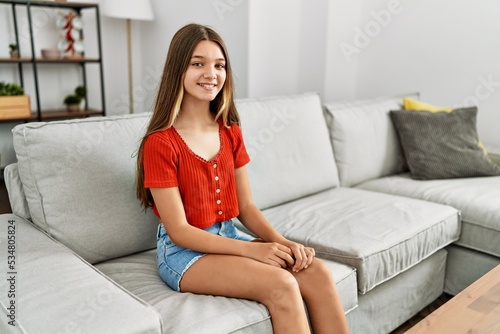 Adorable girl smiling confident sitting on sofa at home