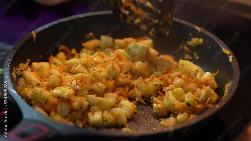 Close-up cooking potatoes. Cooking fried potatoes. A woman's hand stir fried potatoes with spatula in a frying pan. Close-up cooking potatoes. Cooking fried potatoes. A woman's hand stir fried potatoes with spatula in a frying pan.