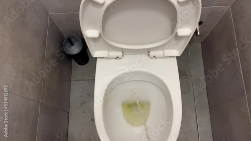 A man urinates in the toilet. A person stands in a modern toilet and urinates in the first person. the stream of urine flies straight into the toilet opening. Modern repair of the toilet room. photo