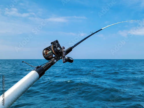 Fototapeta Fishing rod and reel on blue Lake Michigan water