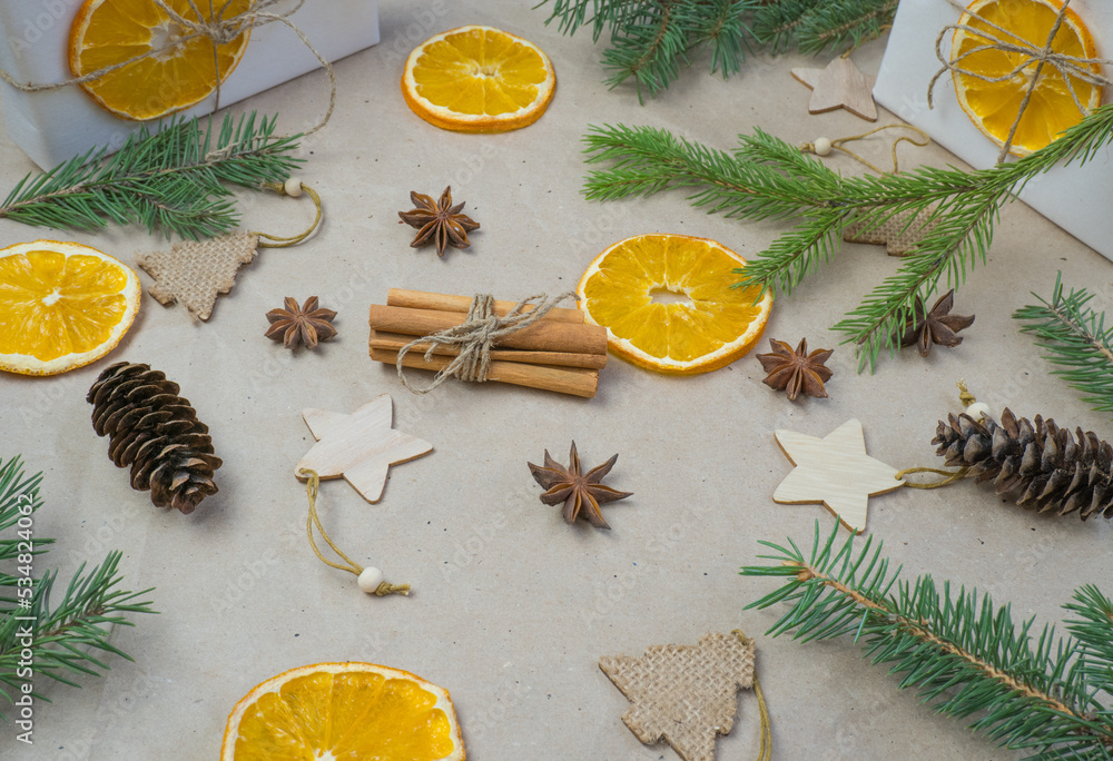 New Year's composition. On beige craft paper, gift boxes, dry orange slices, pine cones, cinnamon, cloves, spruce branches. Cozy Christmas concept. New Year's composition. On beige craft paper, gift boxes, dry orange slices, pine cones, cinnamon, cloves, spruce branches. Cozy Christmas concept.