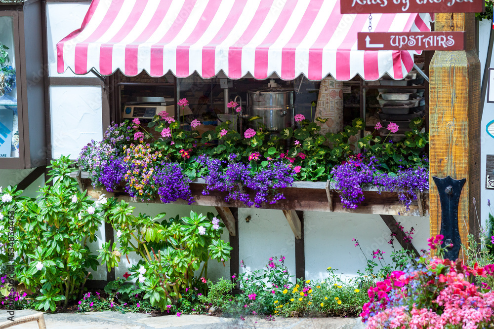 California, 07/11/2011:  Quaint ivy covered shops with flowers and striped awning in Carmel by the sea, city on the Pacific coast known for its enchanting architecture.