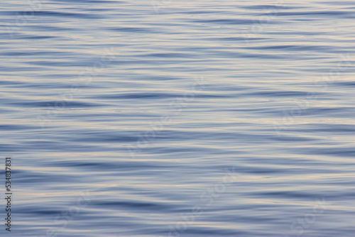 Calm light blue water background with small ripples for banner