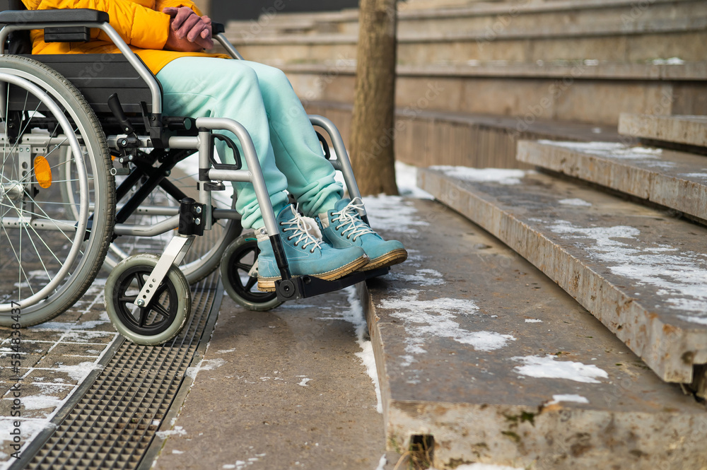Woman in a wheelchair near the stairs in the park in winter. Woman in a wheelchair near the stairs in the park in winter.