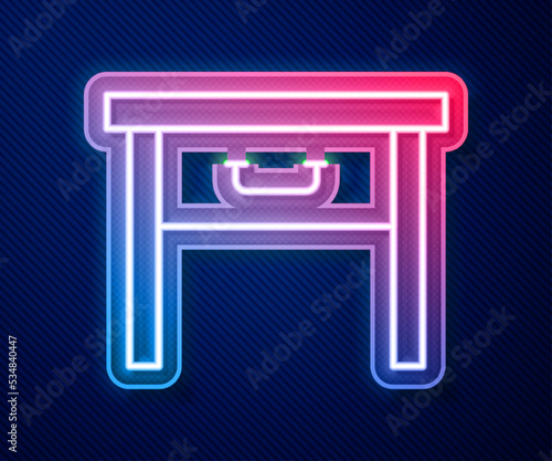 Glowing neon line Furniture nightstand icon isolated on blue background. Vector