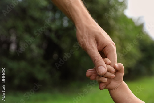 Daughter holding father's hand in park, closeup. Happy family © New Africa