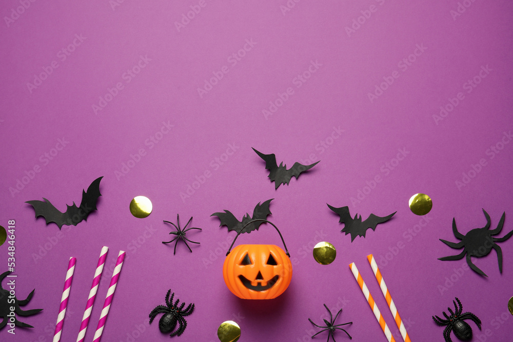 Flat lay composition with plastic pumpkin basket and paper bats on purple background, space for text. Halloween celebration
