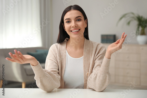 Beautiful young woman conducting webinar in room, camera view photo