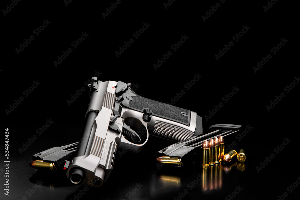Silver black modern gun and ammunition for it on adark  back. Short-barreled weapons for sports and self-defense. Armament for police units, special forces and the army.