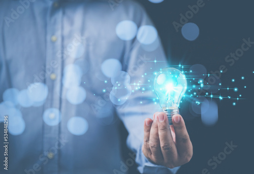 Innovation technology brainstorming to the future on black background. Business, inspiration, and innovation concept. Businessman holding a bright illuminated light bulb on hand with copy space.