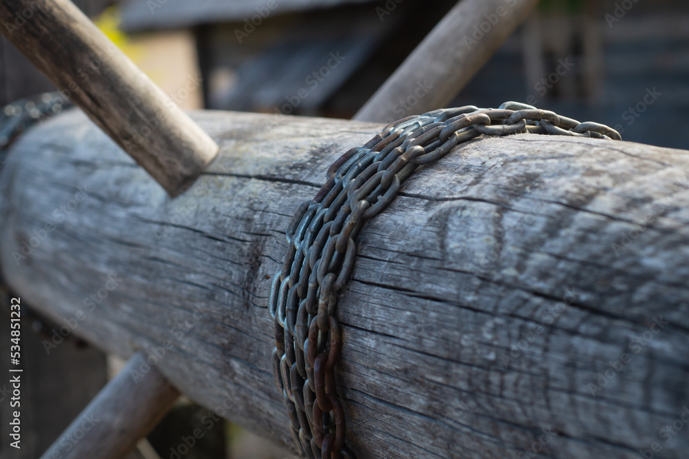 Old wooden winch of well with chain. lifting mechanism of water from the draw well Old wooden winch of well with chain. lifting mechanism of water from the draw well