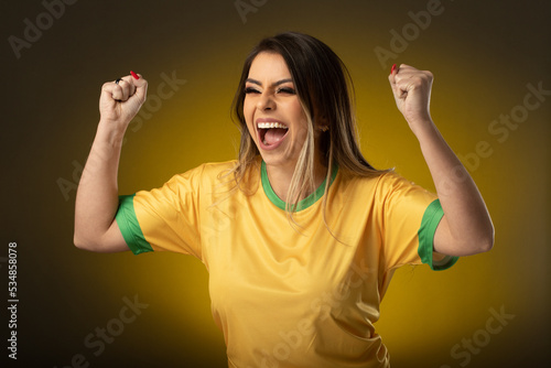 Brazilian fan. Brazilian woman fan celebrating in soccer or soccer match on yellow background. Brazil colors.