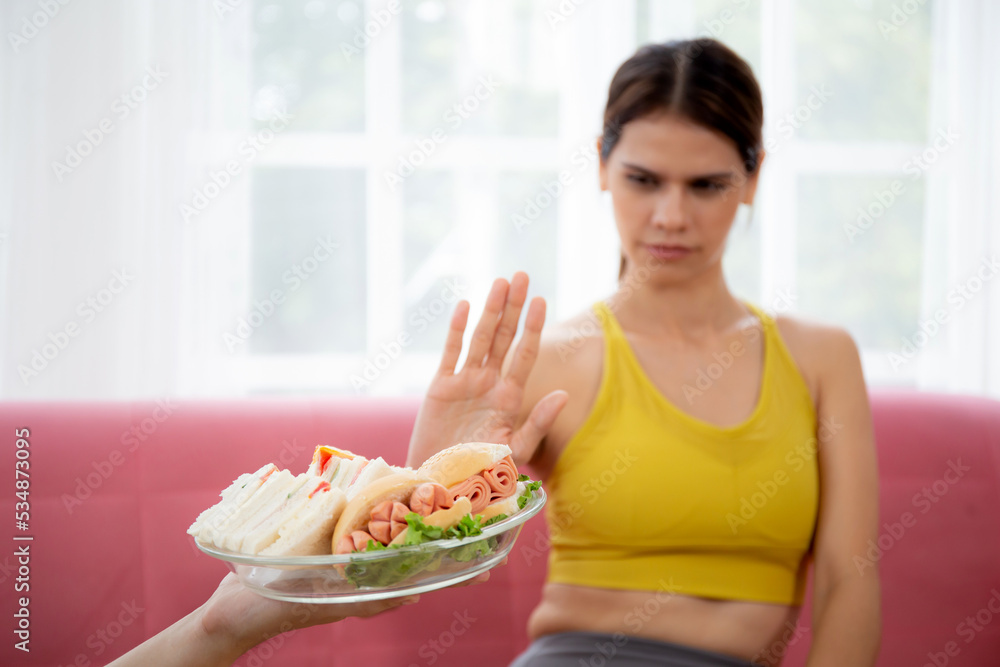 Hands serving food and young caucasian woman making sign say no food unhealthy with obese, woman refuse and push out food with temptation for dieting, nutrition and fast food a bad, health concepts. Hands serving food and young caucasian woman making sign say no food unhealthy with obese, woman refuse and push out food with temptation for dieting, nutrition and fast food a bad, health concepts.