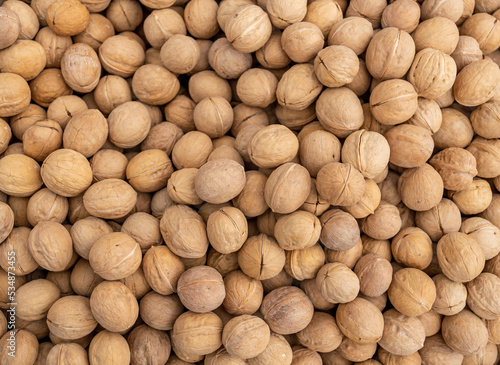 Textured surface of heap of inshell walnuts (unpeeled). Food for amateur. Trade counter with goods ready for sale. photo