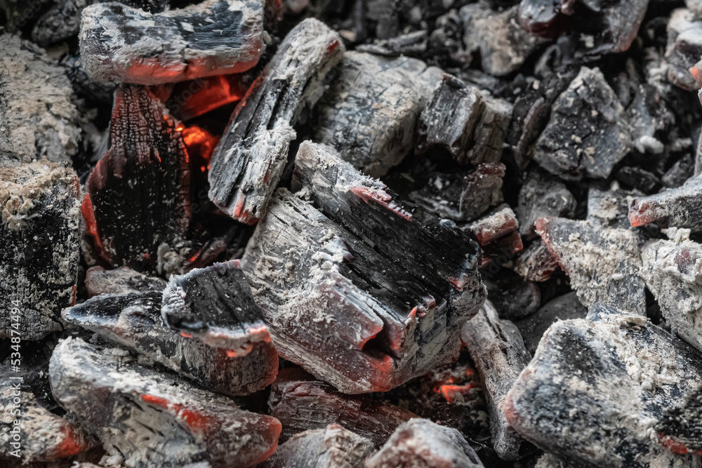 Black embers coals and white ash after a fire. White charred pieces of wood Black embers coals and white ash after a fire. White charred pieces of wood