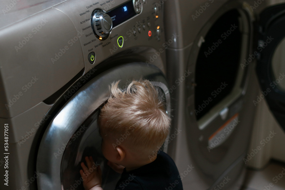 close up of a boy playing with buttons of washing machine close up of a boy playing with buttons of washing machine