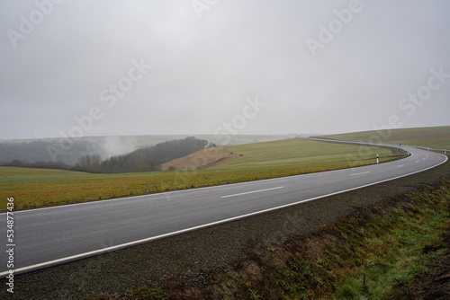 Long rural asphalt road in the landscape on a foggy morning in december 