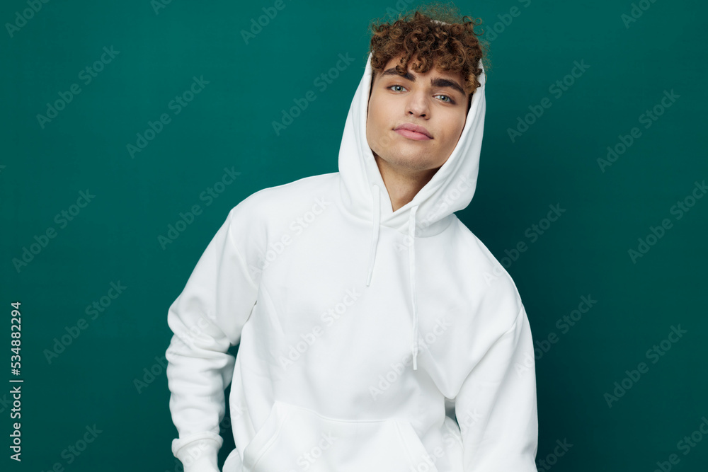 a handsome man stands on a green background in a white hoodie and looks pleasantly into the camera with a slight smile on his face a handsome man stands on a green background in a white hoodie and looks pleasantly into the camera with a slight smile on his face