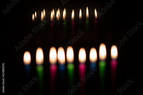 Multi-colored, wax Hanukkah candles burn in a menorah during celebration of the Jewish festival of lights.