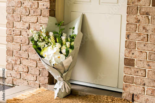 A bouquet of flowers delivered on a porch doorsteps of a house front door. Surprise contactless delivery. Mother's Day, Valentine's Day, Birthday, Celebration and Anniversary concept photo