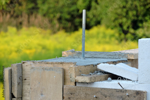 A construction pin, a reinforced concrete beam, steel bars and a wooden formwork on the first floor of a house under construction, walls made of autoclaved aerated concrete photo