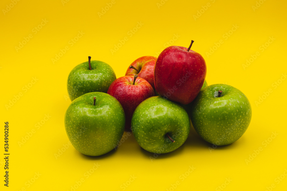 green apples and red apples on yellow background green apples and red apples on yellow background
