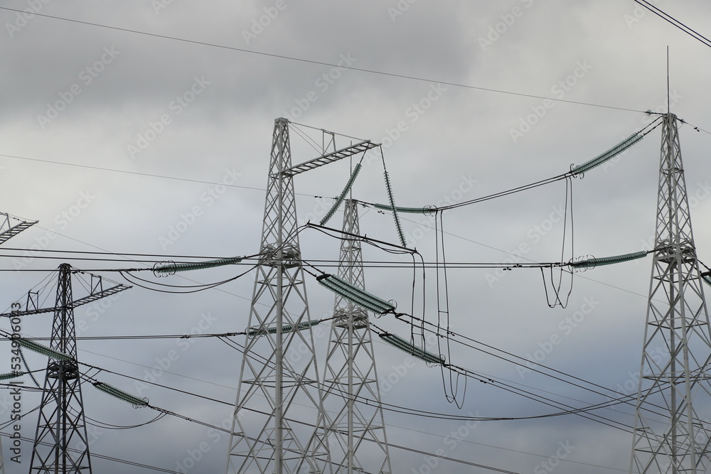 High-voltage power transmission lines against a gloomy sky on an autumn day.