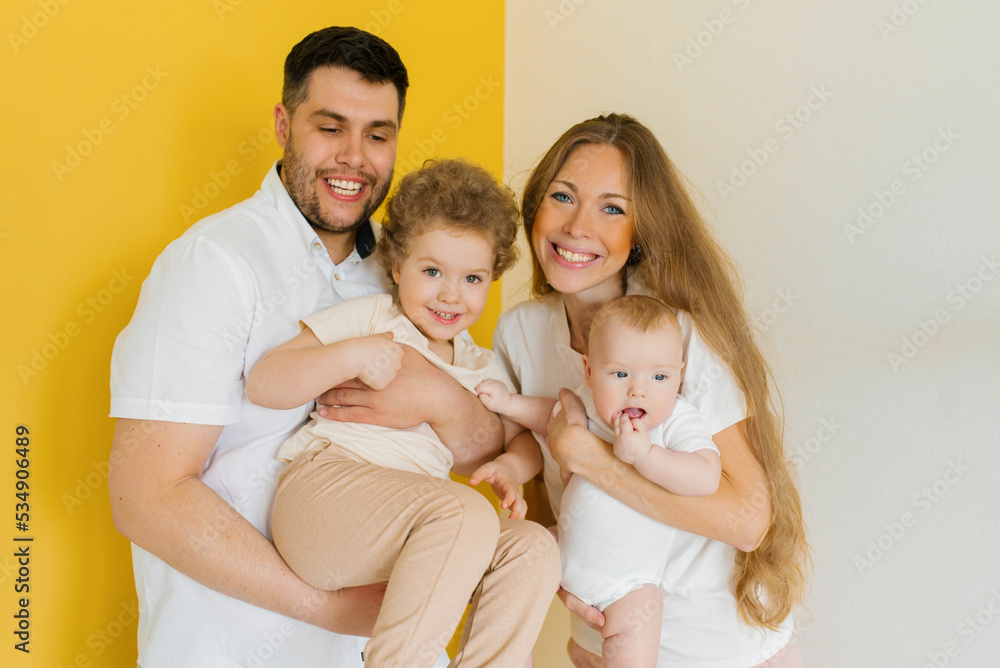 Young sincere family, where a happy father and mother hold their lovely children in their arms. Family photo shoot in the studio