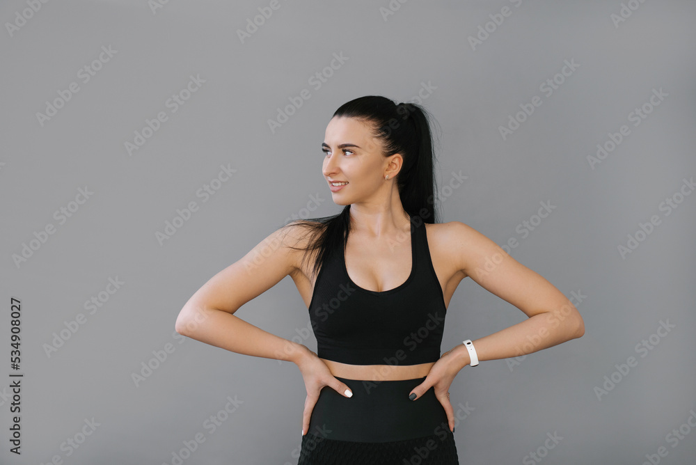 Portrait of a young Caucasian woman dressed in a sports black bra and fashionable trousers on a gray background, the concept of sports and health, coaching Portrait of a young Caucasian woman dressed in a sports black bra and fashionable trousers on a gray background, the concept of sports and health, coaching