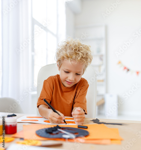 Cute child boy making Halloween home decorations